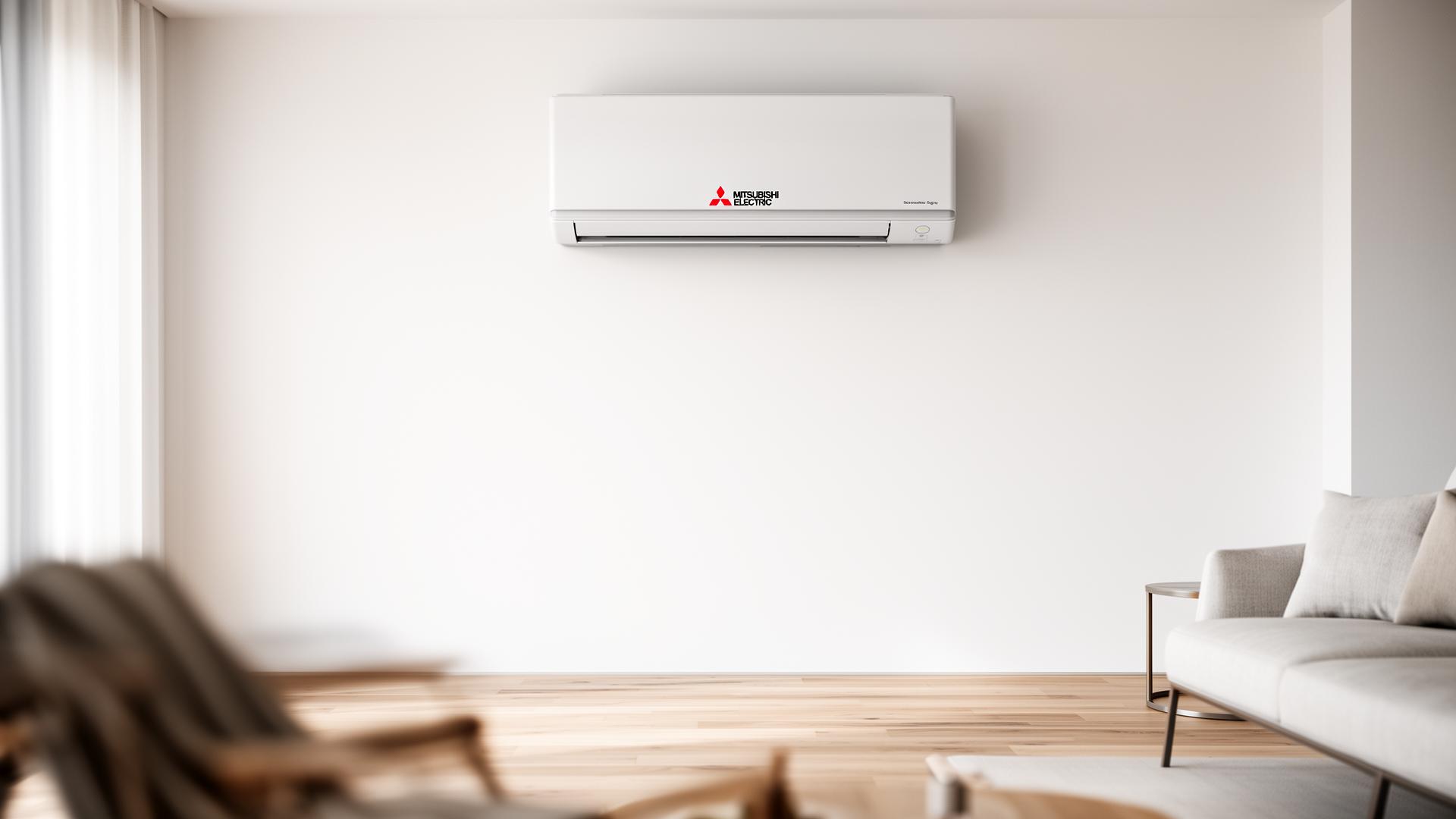 Wall-mounted Mitsubishi Electric ductless mini-split indoor head with the red Mitsubishi logo, installed high on a clean white wall in a minimalist modern living room with light oak floors.