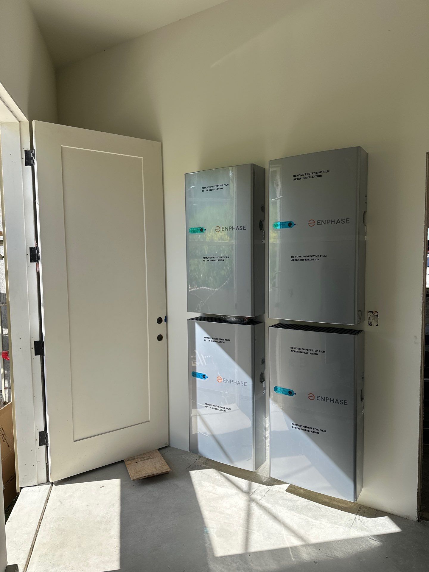 Four Enphase IQ Battery cabinets mounted in a two-by-two grid on an interior utility wall of a new Fremont home, ready for final commissioning.
