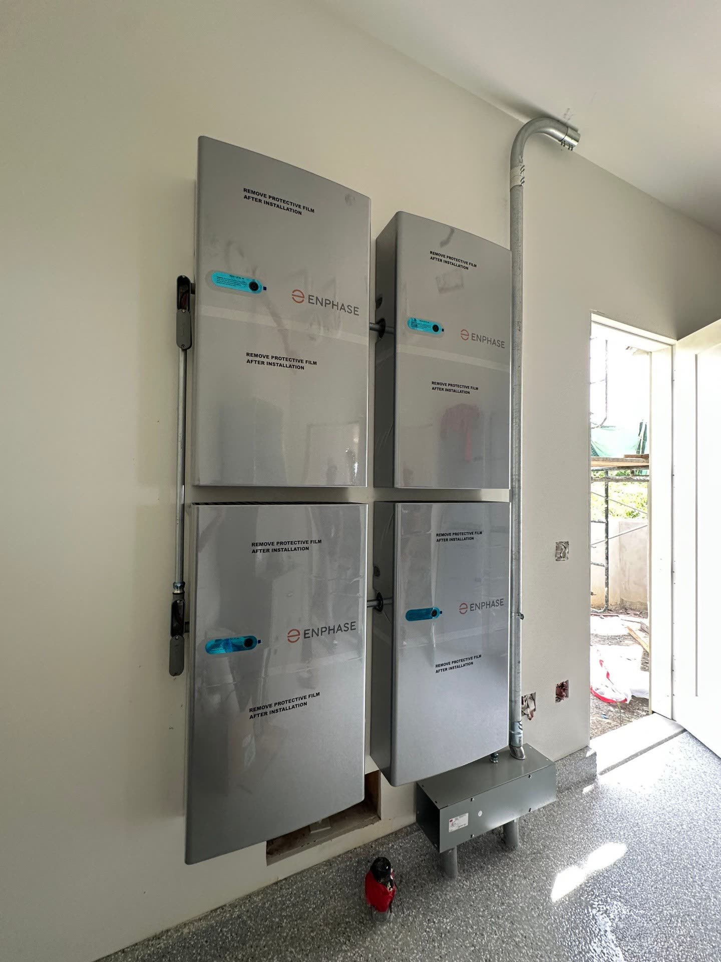 Four Enphase IQ Battery units stacked in a two-by-two configuration on a garage wall of a Fremont home, with conduit routed to a nearby subpanel.