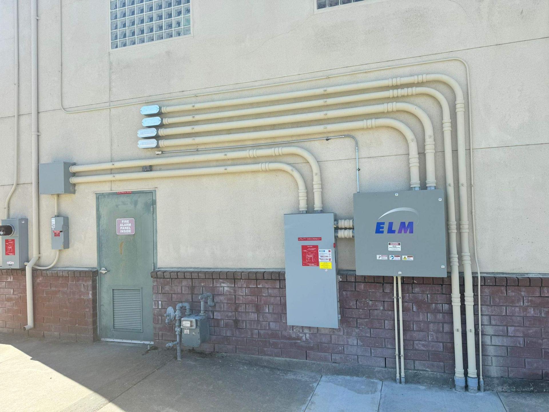 Exterior electrical service wall with ELM main disconnect, Eaton utility disconnect, and neatly organized conduit runs feeding an electrical room at a Healdsburg, CA commercial facility.