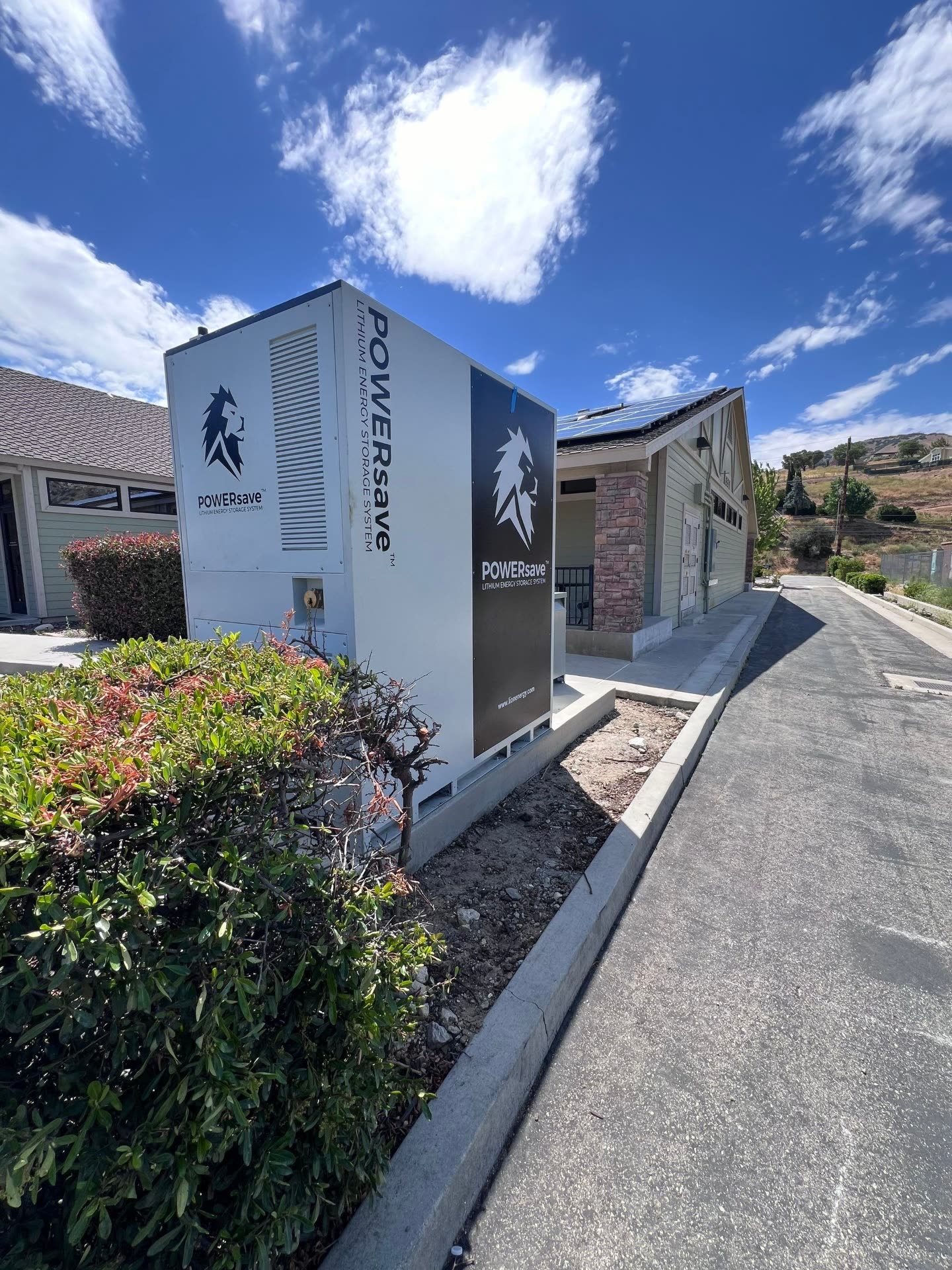 POWERsave commercial lithium energy storage cabinet paired with a rooftop solar system on a Lebec, CA commercial building under a bright blue sky.