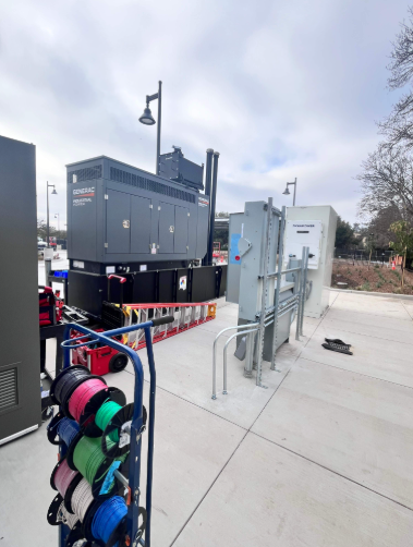 Generac industrial standby generator staged alongside utility switchgear and battery storage equipment during commissioning at a Morgan Hill, CA commercial project.
