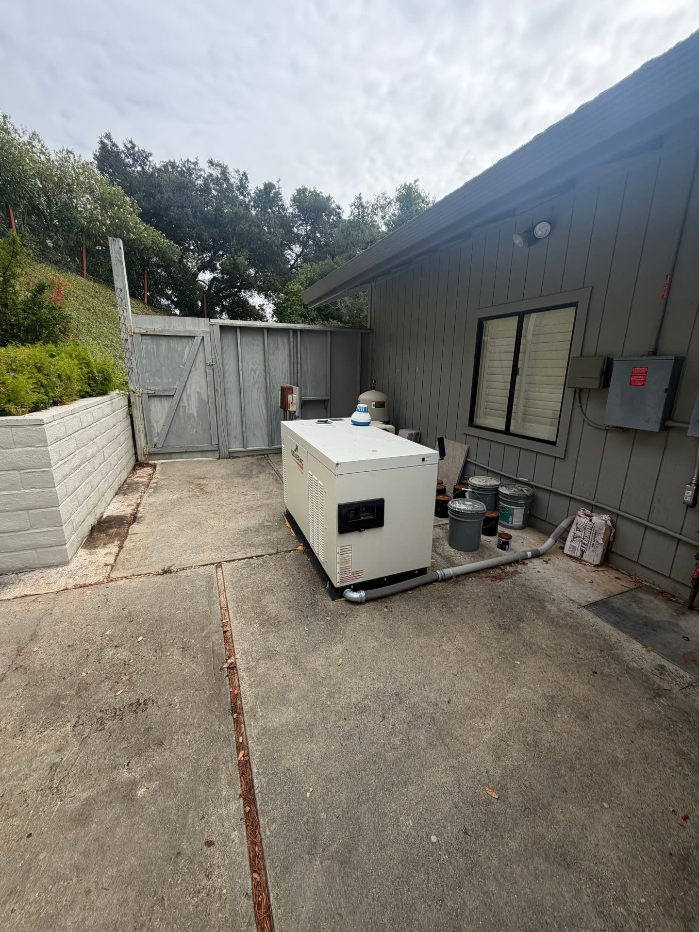 Generac standby generator installed on a concrete pad beside a Morgan Hill home, tied into the utility service for whole-home backup.