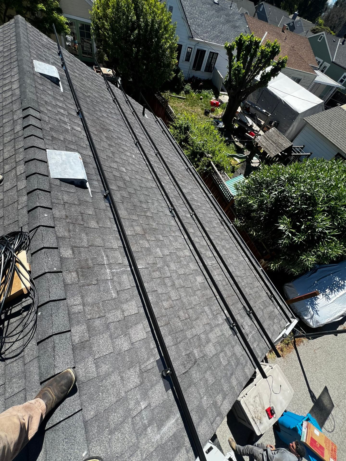 Overhead view of a Santa Clara rooftop with black conduit runs neatly routed along the shingle field between roof penetrations.
