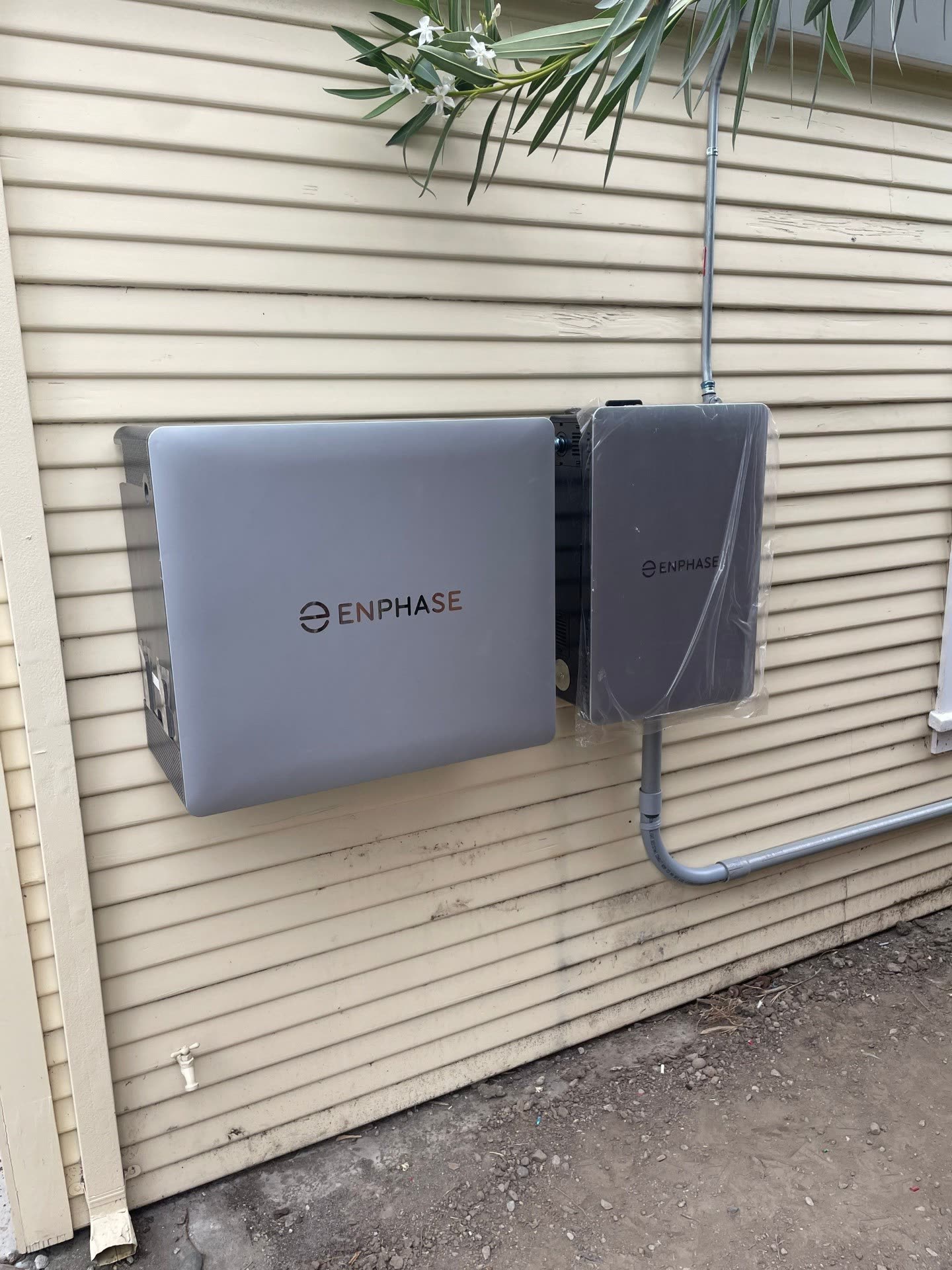 Enphase IQ Battery and system controller mounted side-by-side on the exterior wall of a Santa Clara home, freshly commissioned with protective film still in place.