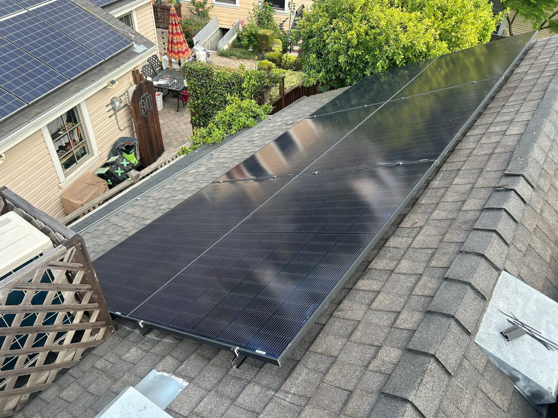 All-black rooftop solar array freshly installed on a Santa Clara home, angled panels lining the ridge with a neighboring solar array in the background.