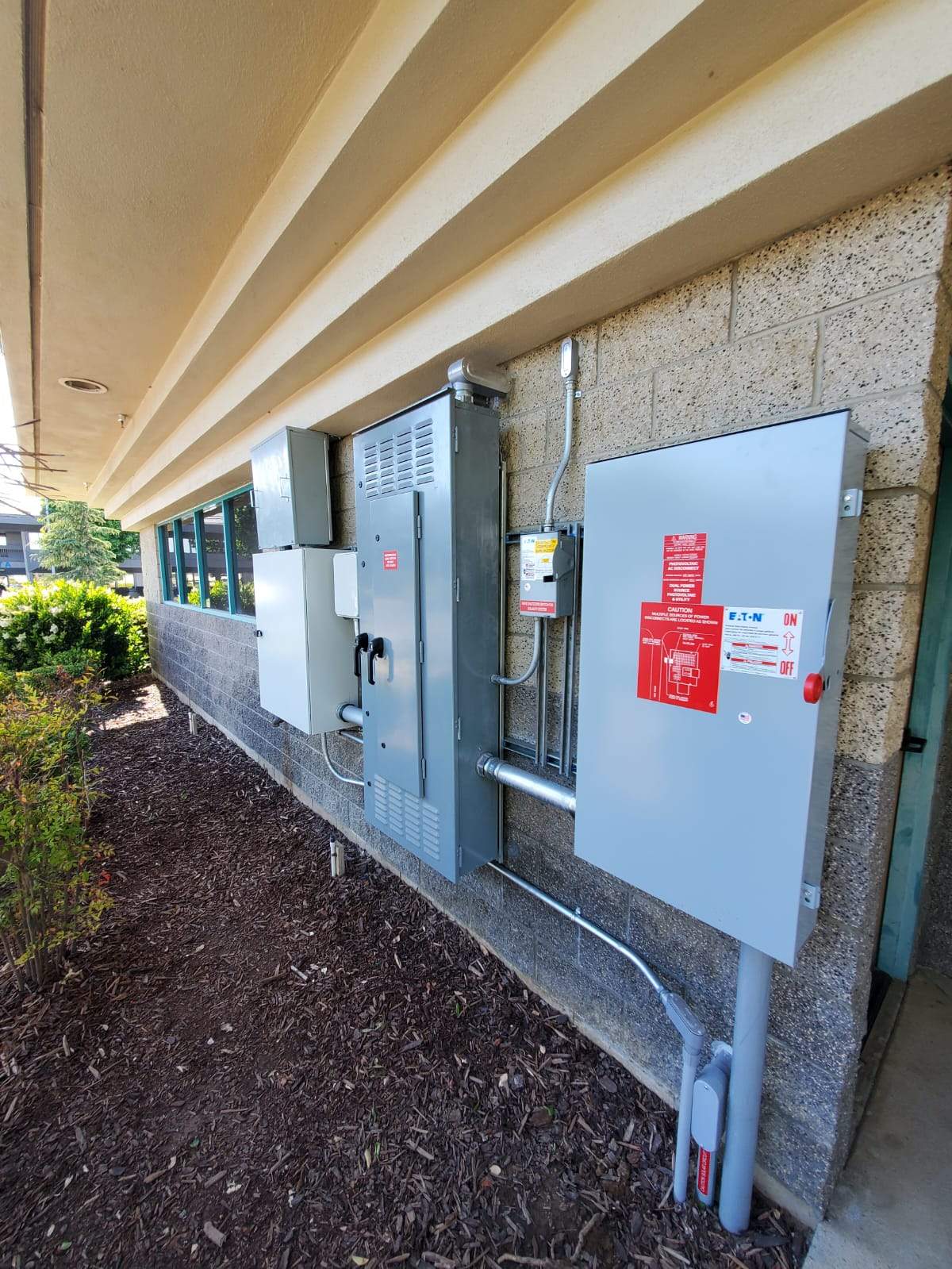 Exterior electrical service equipment for the Santa Maria POWERsave install — utility meter, main disconnect, and Eaton photovoltaic AC disconnect mounted to the commercial building's block wall.