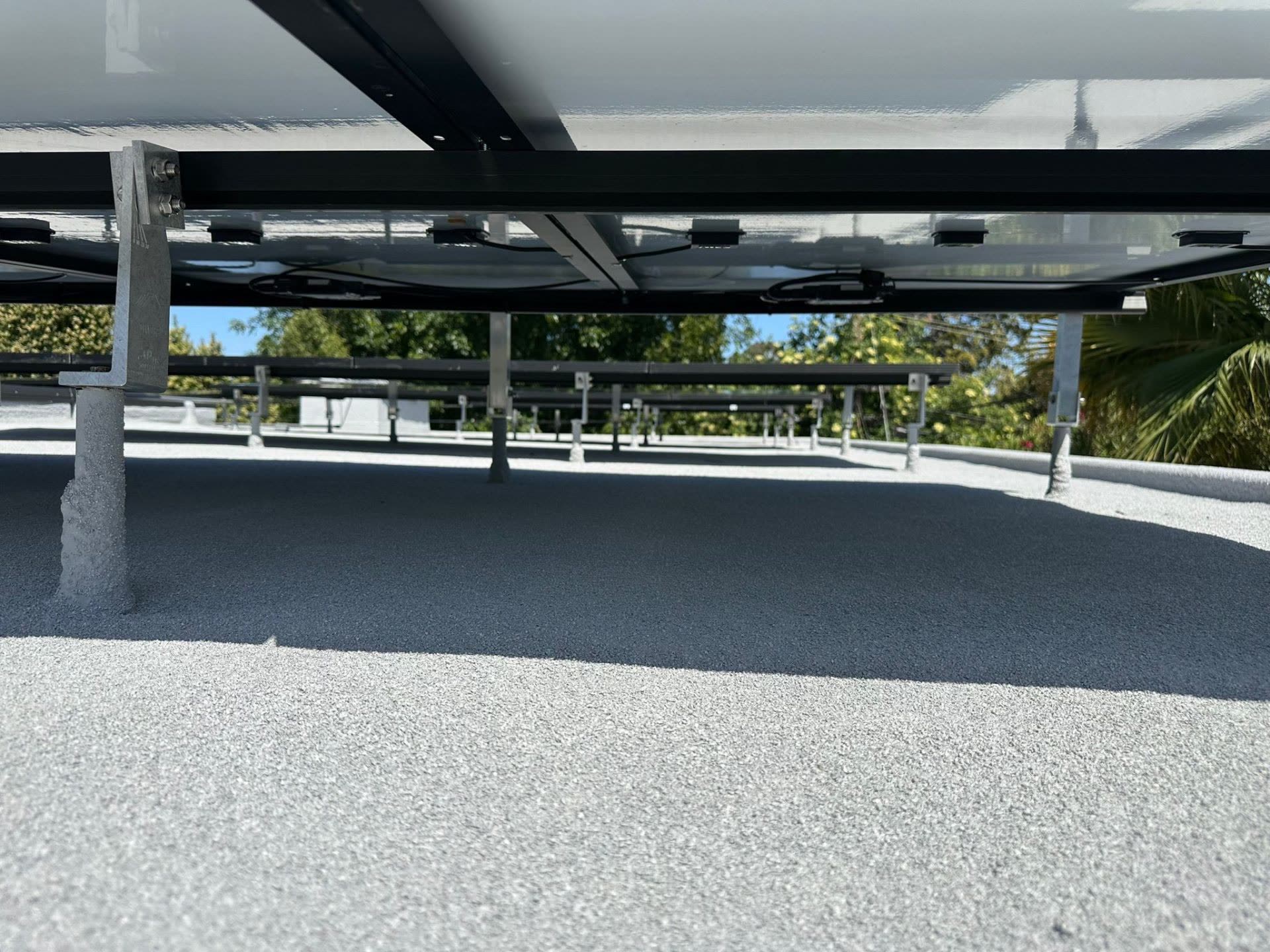 Underside detail of a tilt-racked solar array on a low-slope Sunnyvale roof, showing microinverters, wire management, and clean roof penetrations.